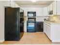 Bright kitchen featuring white cabinets, tile floors, and modern black appliances creating a clean and functional space at 585 S Alton Way # 6B, Denver, CO 80247