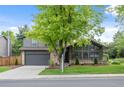 Charming gray two-story home featuring a well-manicured lawn, mature trees, and inviting curb appeal at 11035 E Berry Ave, Englewood, CO 80111