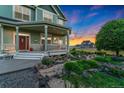 Charming covered porch featuring decorative columns, ample seating, and a serene garden view at 881 Kirby Ct, Watkins, CO 80137
