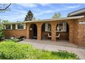 Charming covered porch with brick arches, seating, and manicured front garden beds at 13464 W Virginia Dr, Lakewood, CO 80228