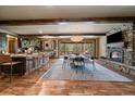 Open-concept living and dining area with a stone fireplace, wood beams, and natural light at 8090 S Homesteader Dr, Morrison, CO 80465