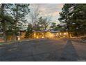 Tan home nestled between mature pine trees with a large driveway on an expansive lot at 7841 Deertrail Dr, Parker, CO 80138