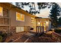 Tan home exterior with a wooden deck and well-lit windows at dusk at 7841 Deertrail Dr, Parker, CO 80138