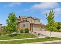 Two-story brick home showcasing a well-manicured lawn, mature trees, and a spacious driveway at 7380 S Shady Grove Way, Aurora, CO 80016