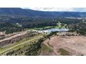 Stunning aerial view featuring a serene lake, golf course, surrounding forests, and rolling hills at 7113 Echo Hills Club Rd, Larkspur, CO 80118