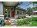 Inviting gray home entrance featuring modern windows, a red door, and well-maintained landscaping at 5 Hillside Dr, Wheat Ridge, CO 80215