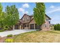 Beautiful two-story home featuring a three-car garage, stone accents, and lush green lawn at 14958 Wistera Way, Broomfield, CO 80023
