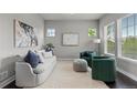 Bright living room featuring a comfortable couch, two green chairs, and large windows with natural light at 23252 E Glidden Dr, Aurora, CO 80016