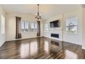 Bright living room featuring hardwood floors, a fireplace, a ceiling fan, and large windows for ample natural light at 14074 Yellow Tip Dr, Parker, CO 80134