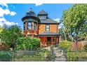 Charming Victorian home with a turret, covered porch, and wrought iron fence, surrounded by lush landscaping at 3015 Lowell Blvd, Denver, CO 80211