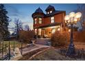 Twilight view of a brick home with a turret, illuminated by ornate streetlights and a welcoming front porch at 3015 Lowell Blvd, Denver, CO 80211