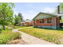 A beautiful shot of a brick home with green trim surrounded by healthy green grass on a sunny day at 4945 Perry St, Denver, CO 80212