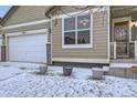 Exterior of a home with a three-car garage, featuring neutral siding and snowy front yard at 1945 Basil St, Strasburg, CO 80136