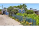 Landscaped front yard with blue picket fence and charming bungalow-style house with lush greenery at 1021 Stuart St, Denver, CO 80204