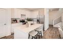 Modern kitchen with stainless steel appliances, white cabinets, and a center island with seating at 485 Bennett Ave, Bennett, CO 80102