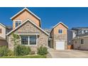 Charming home showcasing stone and wood-style siding, a green lawn, and an attached two-car garage at 17040 Galapago Ct, Broomfield, CO 80023