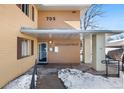 Front entrance of condo building with well marked unit number and wintery landscape at 705 S Clinton # 2A, Denver, CO 80247