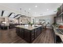 Open-concept kitchen with large island, granite countertops, dark cabinetry, and seamless flow to the living room at 228 Rogers Ct, Castle Rock, CO 80104