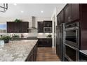 Modern kitchen with stainless steel appliances, granite countertops, and dark wood cabinetry at 228 Rogers Ct, Castle Rock, CO 80104