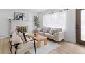 Sun-lit living room featuring modern decor, a cozy fireplace, and stylish light wood floors at 3055 S Winona Ct, Denver, CO 80236