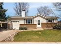 Charming single-story home featuring a brick facade, lush lawn, and inviting landscaping at 9825 W Walker Pl, Littleton, CO 80123