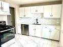 Modern kitchen featuring white cabinets, subway tile backsplash, stainless steel appliances, and marble floors at 7460 W Bails Ave, Lakewood, CO 80232