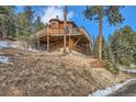 Unique multi-tiered wooden cabin with wraparound deck, set on a wooded lot at 7219 S Brook Forest Rd, Evergreen, CO 80439