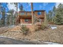 Wood cabin home featuring a multi-level deck, nestled amongst the trees on a lot with a retaining wall at 7219 S Brook Forest Rd, Evergreen, CO 80439