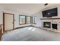 Bright living room with a stone fireplace and large windows showcasing the natural surroundings at 7219 S Brook Forest Rd, Evergreen, CO 80439