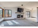 Open living room featuring a stone fireplace and sliding door access to the outdoors at 7219 S Brook Forest Rd, Evergreen, CO 80439