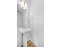 Modern half-bathroom with pedestal sink, mirror and hardwood floors at 1175 Highview Dr, Erie, CO 80516