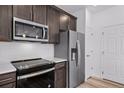 Kitchen features stainless steel appliances, dark wood cabinets, and white subway tile backsplash at 1175 Highview Dr, Erie, CO 80516