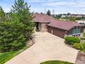 An aerial view of a home with a large driveway, mature trees, and a well-maintained lawn on a sunny day at 23961 E Easter Pl, Aurora, CO 80016