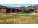 Charming brick home featuring arched entryway, well-manicured lawn, and an attached two-car garage at 14793 E Hampden Pl, Aurora, CO 80014