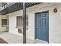 Apartment entrance with a modern blue door, brick facade, and trimmed window at 5875 E Iliff Ave # 115, Denver, CO 80222