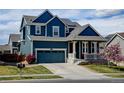 Charming blue two-story home featuring a covered front porch, blue garage door, and a well-manicured lawn at 10733 Salida St, Commerce City, CO 80022