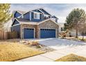 Striking two-story blue home featuring stone accents, three-car garage, and manicured landscaping at 1870 Alpine Dr, Erie, CO 80516