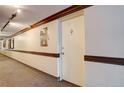 Hallway view with neutral walls, crown and base molding, and wall-mounted fire extinguisher box at 4600 E Asbury Cir # 109, Denver, CO 80222