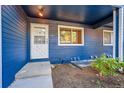 A close up view of the blue exterior siding with a white front door and landscaped green space at 3294 Sentinel Dr, Boulder, CO 80301