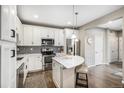 Bright kitchen with stainless appliances, island seating, white cabinets, and modern backsplash at 10066 Belvedere Cir, Lone Tree, CO 80124