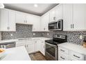 Updated kitchen featuring white cabinetry, stainless appliances, and modern mosaic tile backsplash at 10066 Belvedere Cir, Lone Tree, CO 80124