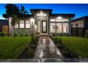 Modern home at dusk featuring manicured lawn, landscape lighting, and a walkway leading to the front door at 4752 Eliot St, Denver, CO 80211