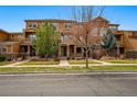 A row of townhouses with wood and stone exteriors, featuring individual covered entrances and landscaping at 5574 W 72Nd Dr, Arvada, CO 80003