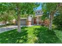 Inviting home with lush green lawn, mature trees, and a brick-accented facade and front-facing two car garage at 14944 E Archer Cir, Aurora, CO 80012