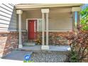Inviting front porch with red brick accents, seating, and a vibrant red front door and ADT security sign at 14944 E Archer Cir, Aurora, CO 80012