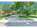 Landscaped front yard with mature trees and a well-maintained lawn leading to a two-car garage at 14944 E Archer Cir, Aurora, CO 80012
