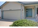 Close up of a home with an attached garage, stone accents and a blue front door at 9784 W Euclid Dr, Littleton, CO 80123