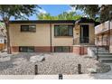 Traditional-style home with a brick facade, decorative rock landscaping, and covered front porch at 1243 Monroe St, Denver, CO 80206