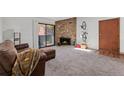 Bright living room featuring a stone fireplace, sliding glass doors and plush carpeting at 11905 E Harvard Ave # 208, Aurora, CO 80014