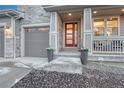 Inviting front porch with decorative columns and a modern red front door at 2775 Morningbird Ln, Castle Rock, CO 80109
